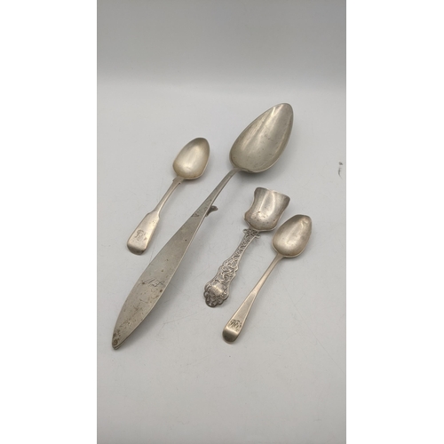 63 - A white metal Continental basting spoon, along with two teaspoons and silver caddy spoon with a flor... 