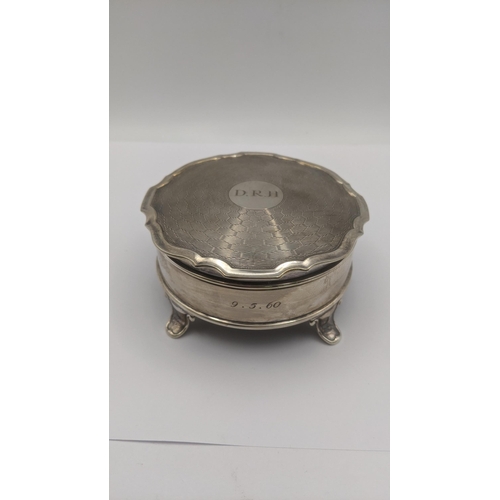 74 - An silver dressing table ring box in circular form on four feet having an engine turned lid engraved... 