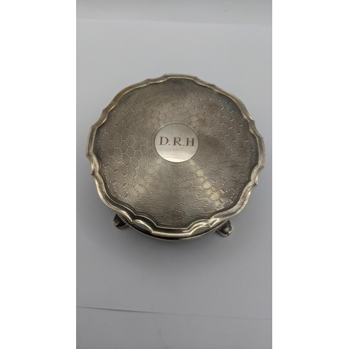 74 - An silver dressing table ring box in circular form on four feet having an engine turned lid engraved... 