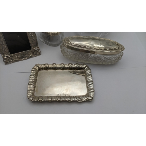 76 - Silver dressing table collectables to include an heart shaped glass and silver lidded pot having flo... 