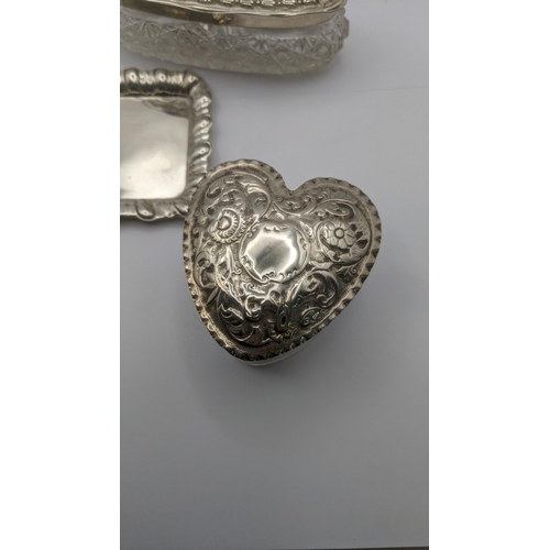 76 - Silver dressing table collectables to include an heart shaped glass and silver lidded pot having flo... 