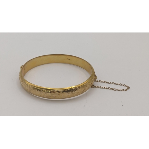 81 - A 9ct yellow gold hinged bangle having floral engraved decoration and safety chain, 10g
Location:CAB... 