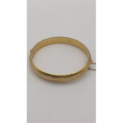 81 - A 9ct yellow gold hinged bangle having floral engraved decoration and safety chain, 10g
Location:CAB... 