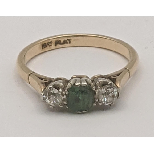 83 - An emerald and diamond ring, central emerald flanked by two brilliant cut diamonds in a platinum cla... 