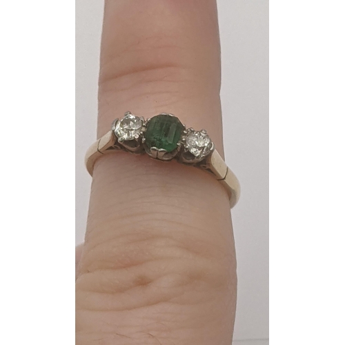 83 - An emerald and diamond ring, central emerald flanked by two brilliant cut diamonds in a platinum cla... 