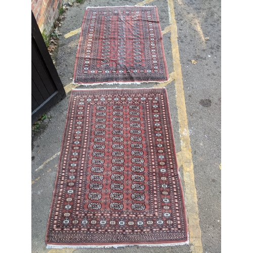 311 - TWo hand woven red ground Pakistan Bukhara rugs, three  vertical rows of 14 elephant gulls, alternat... 