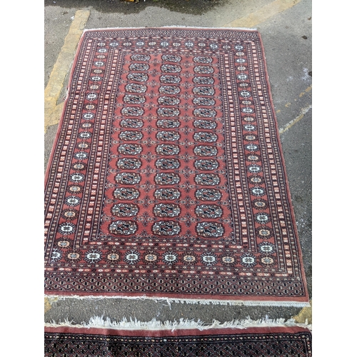 311 - TWo hand woven red ground Pakistan Bukhara rugs, three  vertical rows of 14 elephant gulls, alternat... 