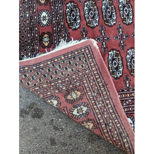 311 - TWo hand woven red ground Pakistan Bukhara rugs, three  vertical rows of 14 elephant gulls, alternat... 