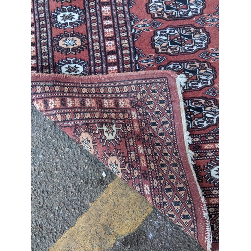 311 - TWo hand woven red ground Pakistan Bukhara rugs, three  vertical rows of 14 elephant gulls, alternat... 