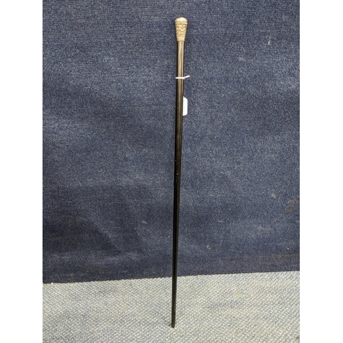 471 - A late Victorian/Edwardian ebonized and white metal walking cane, the repousse decorated knop having... 