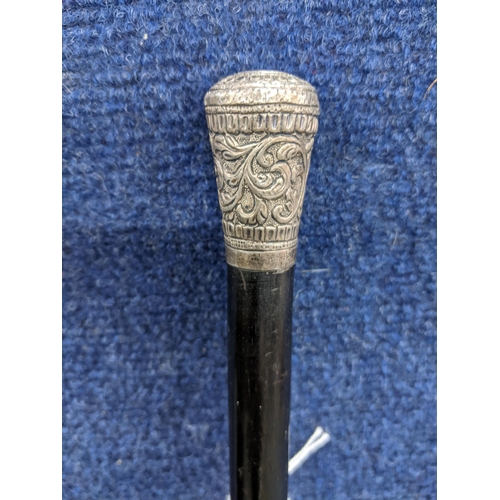 471 - A late Victorian/Edwardian ebonized and white metal walking cane, the repousse decorated knop having... 