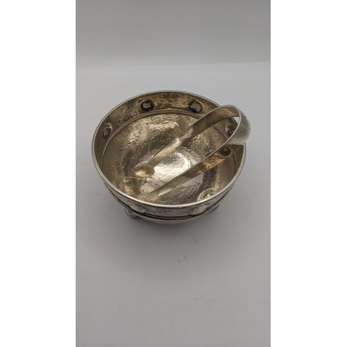 136 - An Arts & Crafts A.E. Jones silver sugar bowl on four ball feet with hammered design, and a pair of ... 