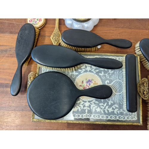 377 - A dressing table set with embroidered ornament, tray, clock, brushes, mirror, candlestick and an ebo... 