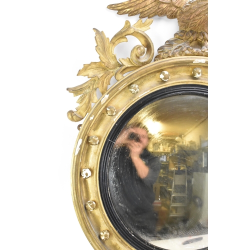 236 - A Regency wall mirror, having a convex plate in a gilt moulded and carved giltwood frame with a ball... 