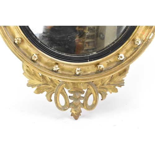 236 - A Regency wall mirror, having a convex plate in a gilt moulded and carved giltwood frame with a ball... 