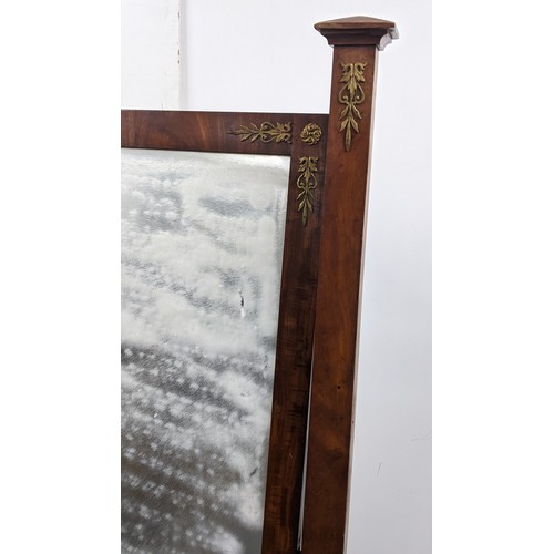 245 - A 19th century French empire cheval mirror, the swing mirror supported by two tapering columns and e... 