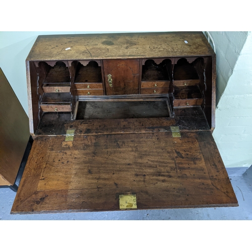 70 - A George III oak bureau, fall flap revealing a pigeonhole and drawer interior, with slide and secret... 