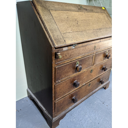 70 - A George III oak bureau, fall flap revealing a pigeonhole and drawer interior, with slide and secret... 