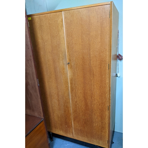 73 - A mid century Ebenezer Gomme for G-Plan blond oak bedroom cabinet, twin doors with key, standing on ... 