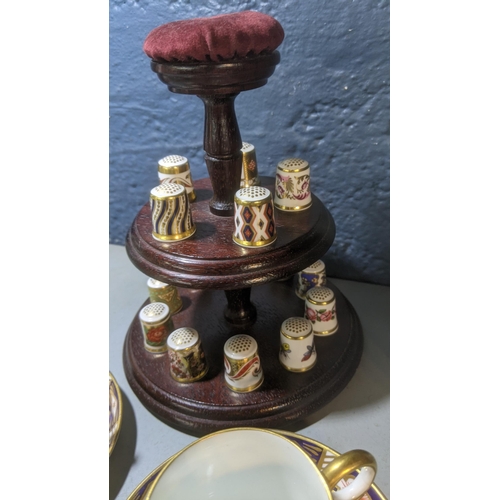 357 - A collection of 15 Royal Crown Derby thimbles on a stand with a pair of coffee cans and Aynsley
Loca... 