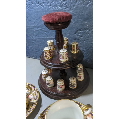 357 - A collection of 15 Royal Crown Derby thimbles on a stand with a pair of coffee cans and Aynsley
Loca... 