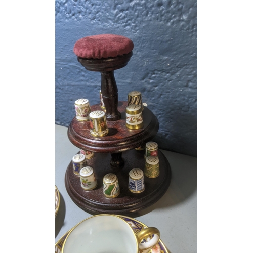 357 - A collection of 15 Royal Crown Derby thimbles on a stand with a pair of coffee cans and Aynsley
Loca... 