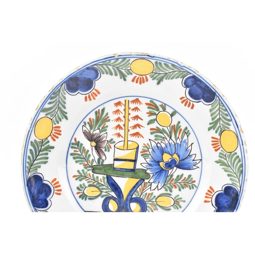 525 - Two 18th century Dutch Delft polychrome plates, one depicting a still life of flowers and a table in... 