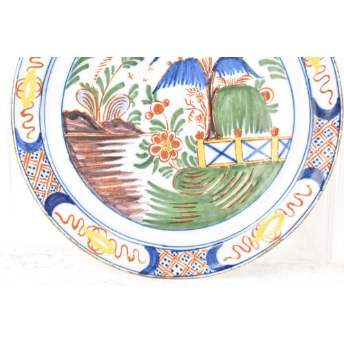 525 - Two 18th century Dutch Delft polychrome plates, one depicting a still life of flowers and a table in... 