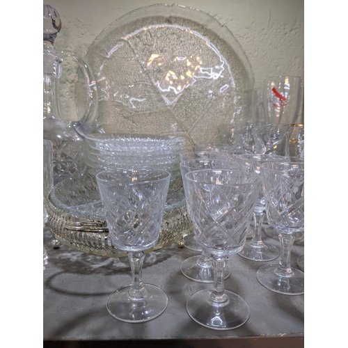 524 - A collection of glassware to include decorative plates, drinking glasses, decanters, serving jugs, b... 