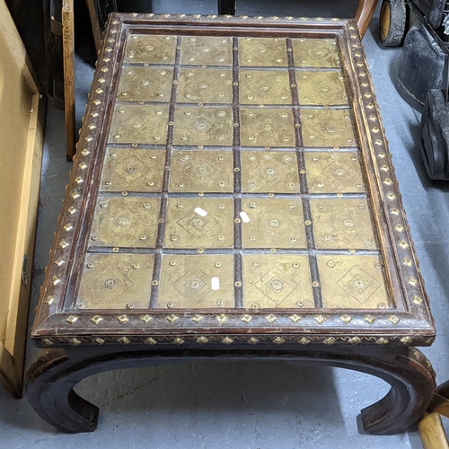 405 - An Indian teak coffee table having a brass panelled top, applied studs and on bowed legs, 40cm h x 9... 