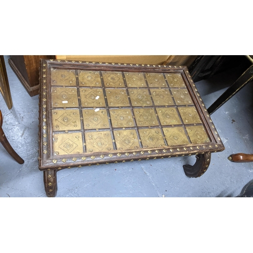 405 - An Indian teak coffee table having a brass panelled top, applied studs and on bowed legs, 40cm h x 9... 