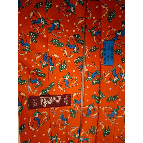 7 - Hermes- An orange silk scarf with images of skiers, snow and fir trees together with orange branded ... 