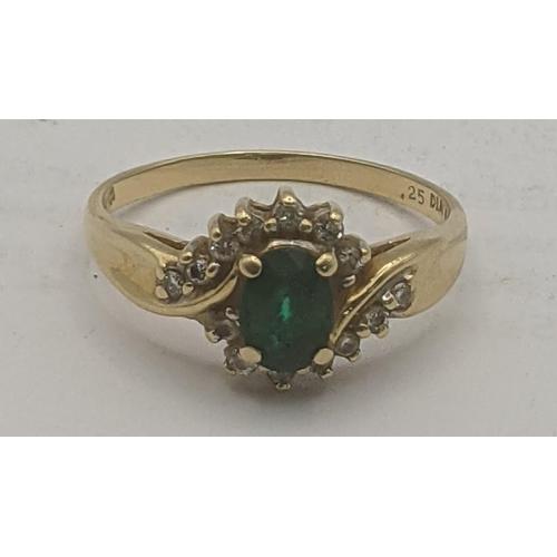 63 - A 18ct yellow gold emerald and diamond ring, an oval cut emerald in a four claw setting surrounded b... 