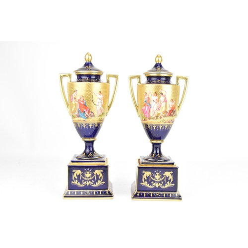 110 - A Pair of circa 1900 blue ground Vienna urn shaped vases, with lids and plinths, hand-painted with s... 