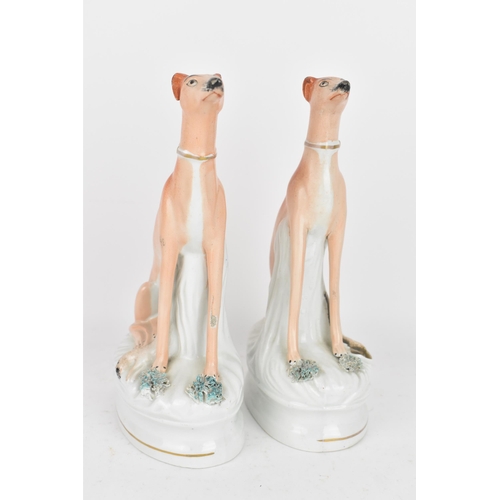 98 - A pair of Victorian Staffordshire pottery greyhounds, modelled seated with free-standing fore-legs, ... 