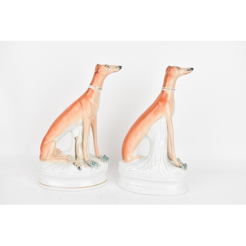 98 - A pair of Victorian Staffordshire pottery greyhounds, modelled seated with free-standing fore-legs, ... 