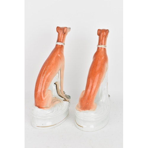 98 - A pair of Victorian Staffordshire pottery greyhounds, modelled seated with free-standing fore-legs, ... 