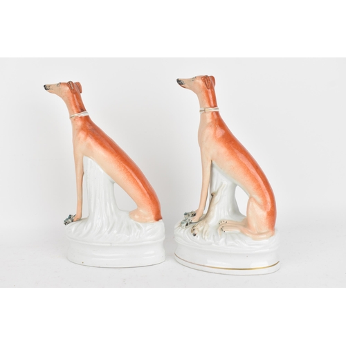 98 - A pair of Victorian Staffordshire pottery greyhounds, modelled seated with free-standing fore-legs, ... 