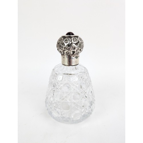 55 - An Edwardian glass scent bottle with a silver screw cap, embossed with flowers and topped with a red... 