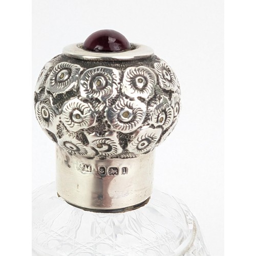 55 - An Edwardian glass scent bottle with a silver screw cap, embossed with flowers and topped with a red... 