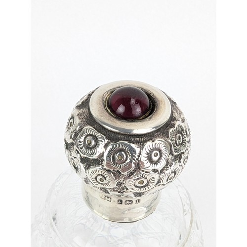 55 - An Edwardian glass scent bottle with a silver screw cap, embossed with flowers and topped with a red... 