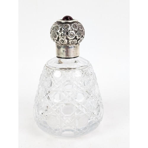 55 - An Edwardian glass scent bottle with a silver screw cap, embossed with flowers and topped with a red... 