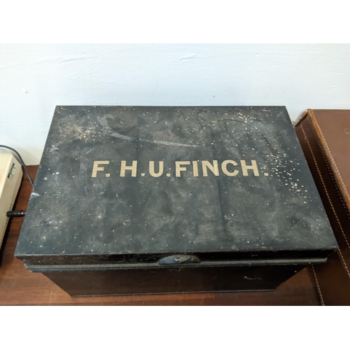 256 - A group of vintage containers to include two suitcases, a metal box labelled FHU Finch, a single rec... 