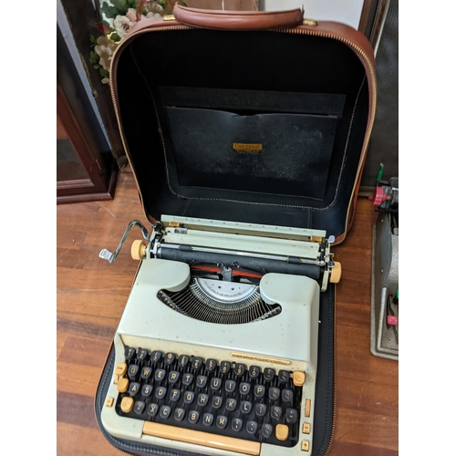 445 - A mixed lot to include two vintage typewriters, a display cabinet, a fire screen, and a mirrored wal... 