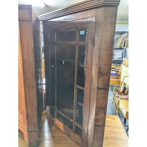 363 - A Georgian mahogany veneered corner cabinet, internal shelves on a base with twin arched doors on br... 