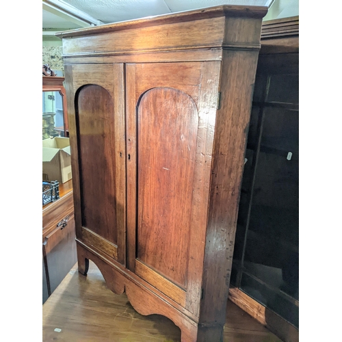 363 - A Georgian mahogany veneered corner cabinet, internal shelves on a base with twin arched doors on br... 