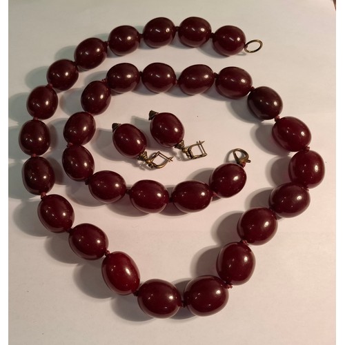 41 - A vintage cherry amber resin suite comprising a necklace of 31 large oval beads, approx 87cm total l... 