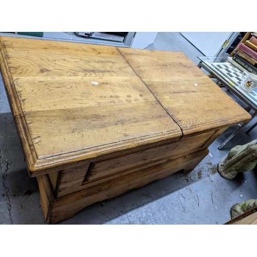 182 - A solid oak coffee table with a double opening hinged to providing storage inside, measuring 106cm x... 