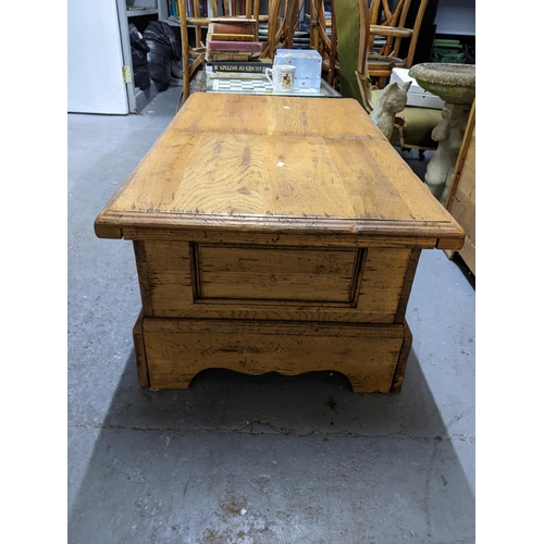 182 - A solid oak coffee table with a double opening hinged to providing storage inside, measuring 106cm x... 