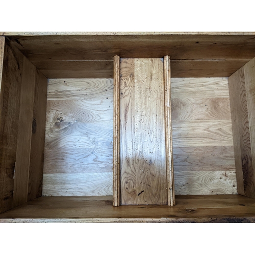 182 - A solid oak coffee table with a double opening hinged to providing storage inside, measuring 106cm x... 